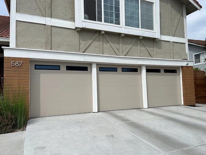 Triple-car tan garage doors with black glass window accents